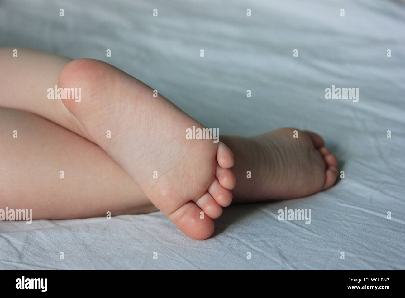 The baby`s feet. The toddler is sleeping on the bed. Closeup the cute foot Stock Photo